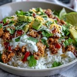 A finished Turkey Taco Bowl features fluffy rice, seasoned turkey, shredded lettuce, salsa, and a lime wedge on the side.