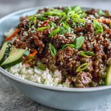 Savory Korean Ground Beef Bowl over fluffy rice topped with crisp pickled carrots and cucumbers.