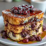 Warm blueberry pancake casserole fresh from the oven, drizzled with maple syrup for a cozy breakfast treat.  