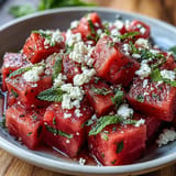 Close-up of chilled watermelon chili lime salad with mint, glistening with zesty lime dressing.