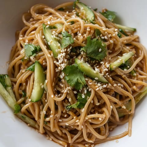 Spicy Sesame Noodle Salad served in a white bowl, garnished with chopped spring onions, toasted sesame seeds, and roasted peanuts for a satisfying crunch.