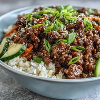 Savory Korean Ground Beef Bowl over fluffy rice topped with crisp pickled carrots and cucumbers.