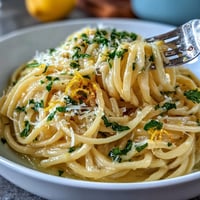Easy Lemon Butter Pasta in a creamy sauce with fresh lemon zest and grated Parmesan cheese, garnished with parsley and served in a white bowl.